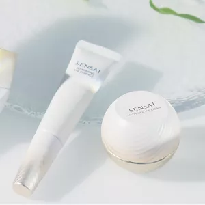 Refreshing Eye Essence tube on glass plate and Melty Rich Eye Cream jar on white surface next to each other